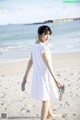 A woman in a white dress walking on the beach.