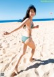 A woman in a bikini running on the beach.